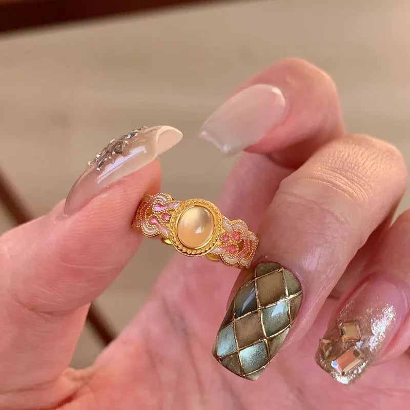 Geometric open ring for women with pink crystal enamel decoration on a gold-toned band.