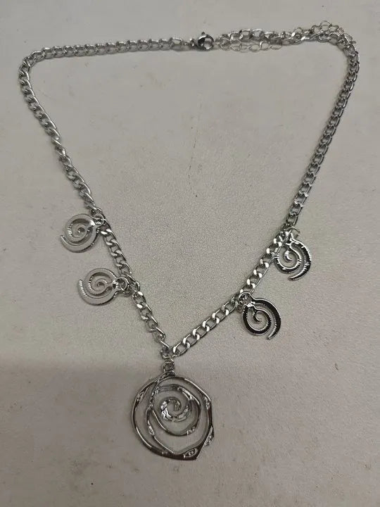Geometric spiral donut jewellery set with gold necklace, bracelet, and ear hooks on dark background