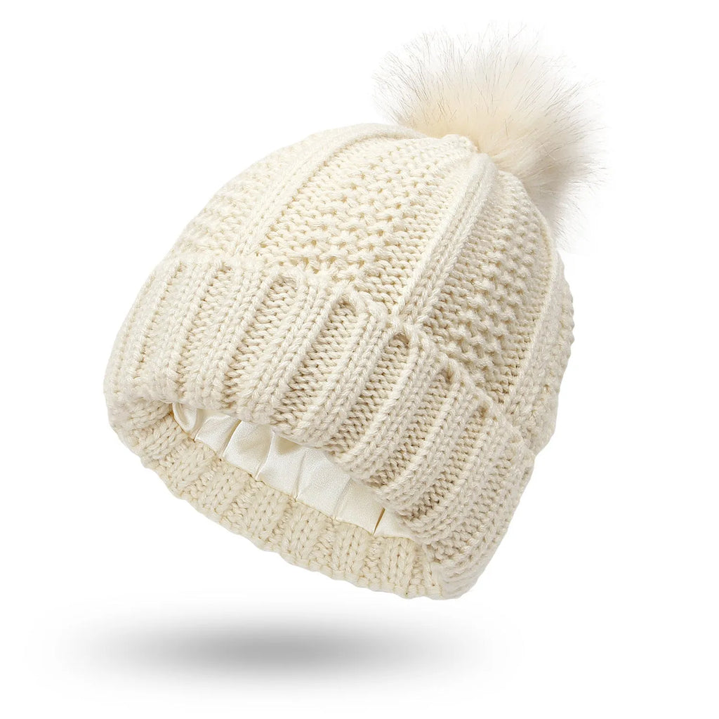 Women's knit beanie hat with faux fur pom pom and satin lining in wine red colour.