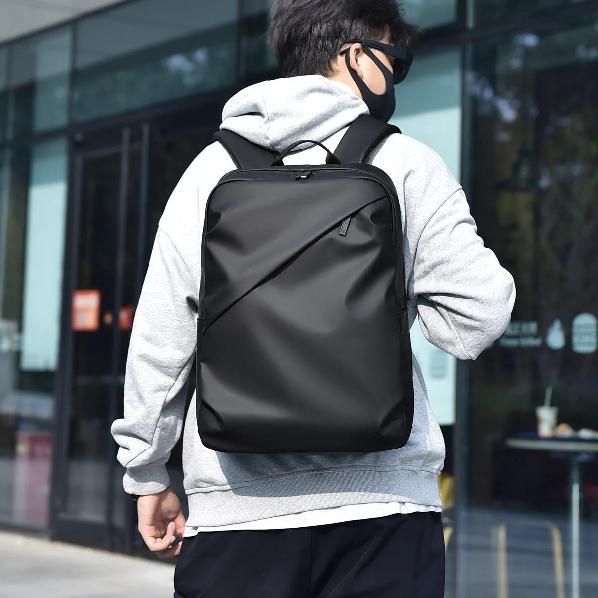 Large black waterproof PU backpack with sewing thread details and separate laptop bag