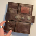 Brown A7 leather buckle notebook with loose-leaf binding on wooden surface