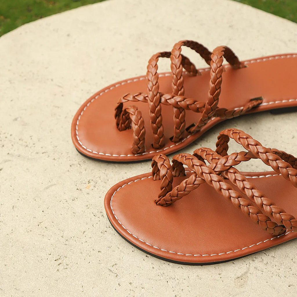 Women's flat woven sandals with a clip-toe design in white, shown on a foot.