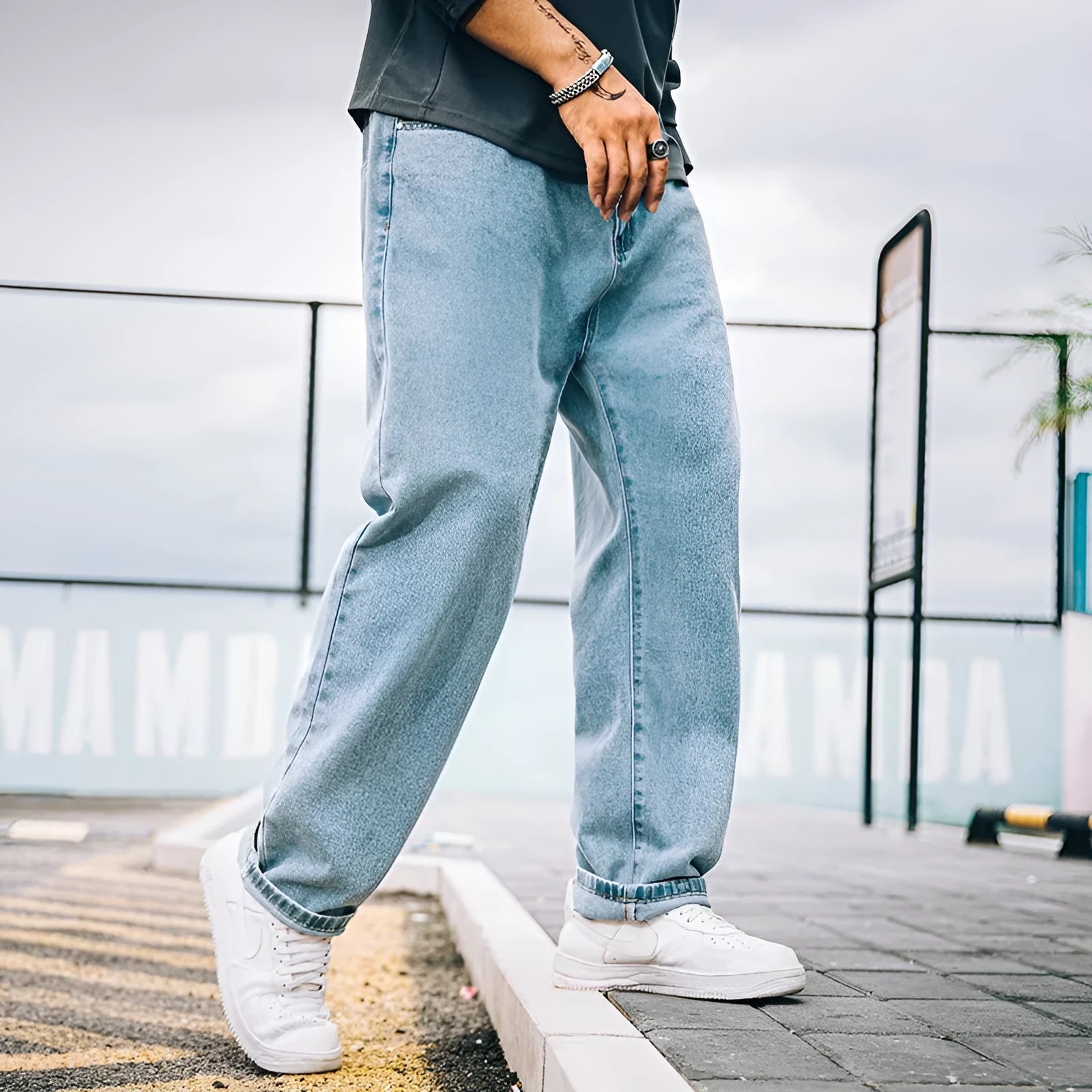 Men's loose straight-cut blue jeans on a plain background, showing the mid waist and zipper fly detail.