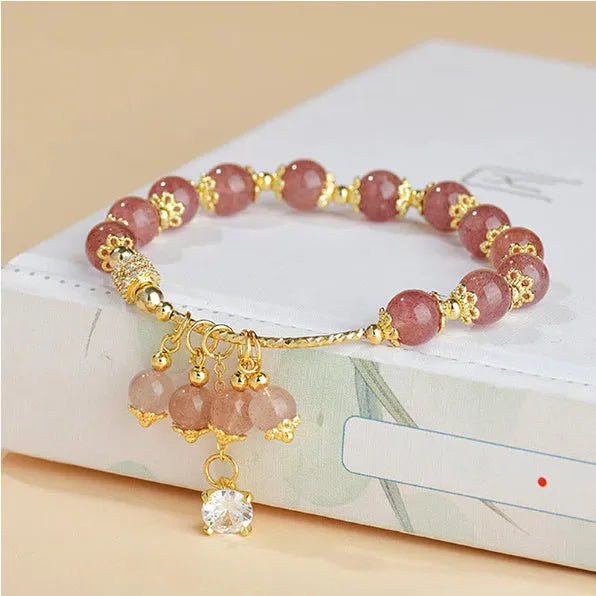 Pink heart-shaped strawberry quartz and pearl women's bracelet on a wrist.
