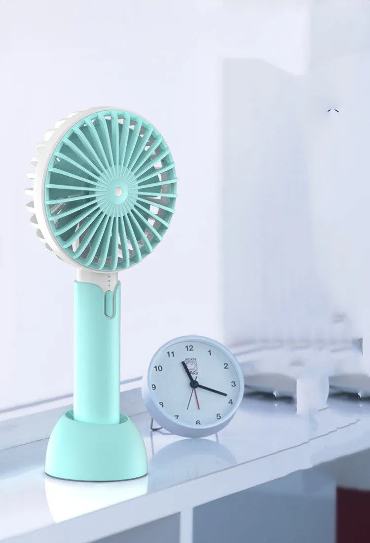 Blue handheld USB mini fan with three-speed buttons and oscillation function on a desk.
