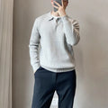 Man wearing a loose fit, textured grey knitted sweater with long sleeves for casual autumn wear.