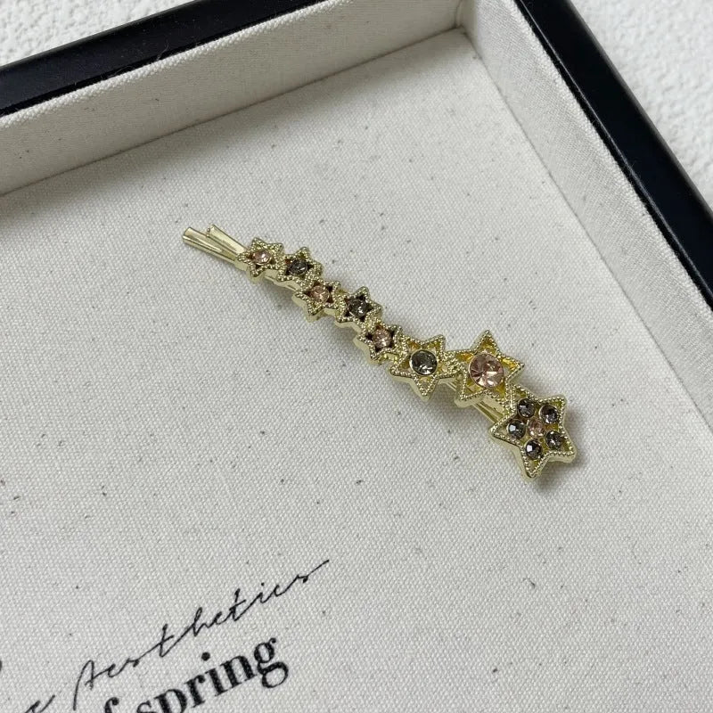 Golden hair clip barrette with a rhinestone five-pointed star, shown on a side angle.