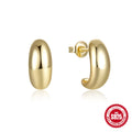Close-up of a glossy C-shaped sterling silver stud earring with a gold electroplated finish.