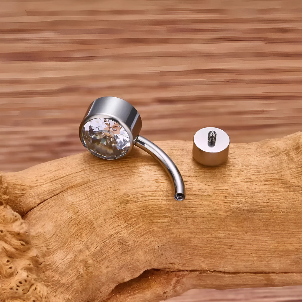 Double-headed titanium alloy navel stud with zirconium accents in various colours on a plain background.