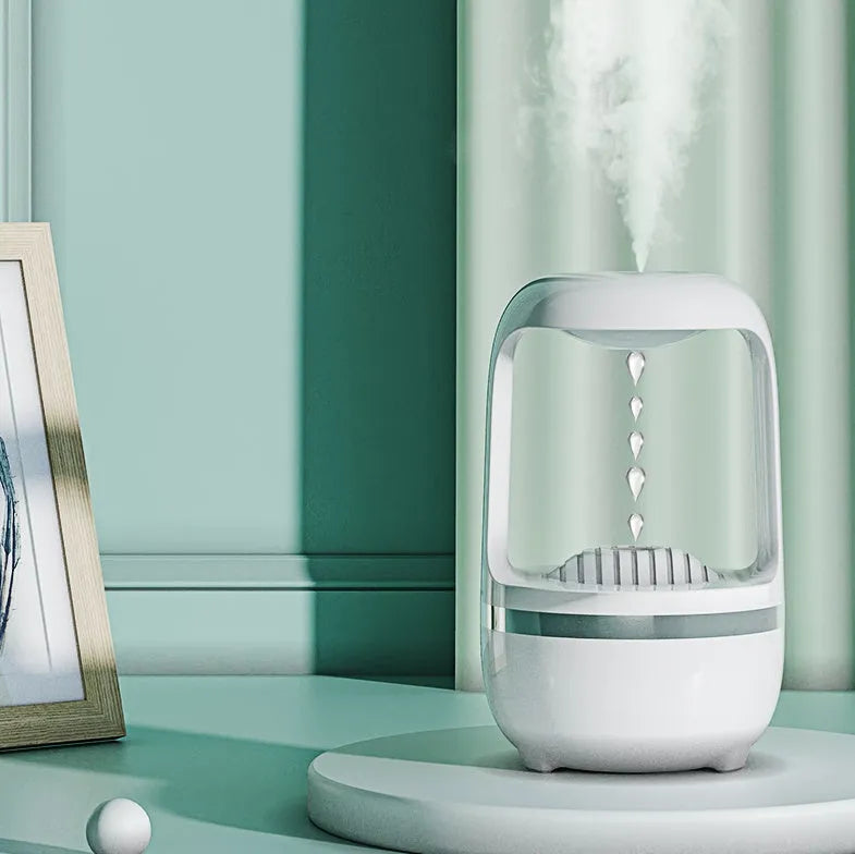 White anti-gravity humidifier with floating water droplet on a desk next to a USB cable