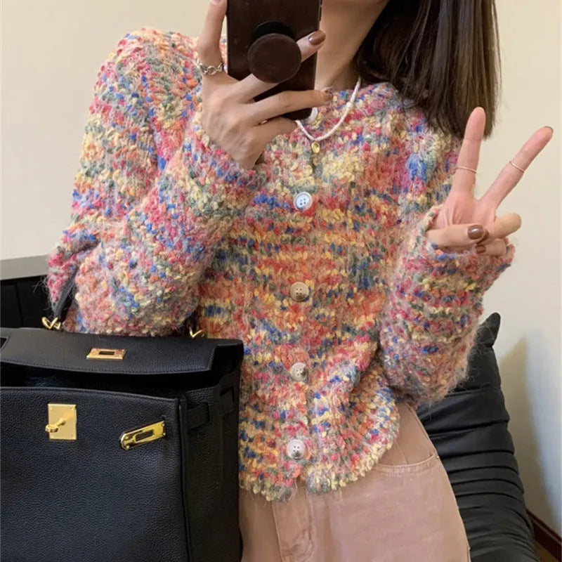 Pink and green retro rainbow patterned knitted cardigan sweater on a hanger.