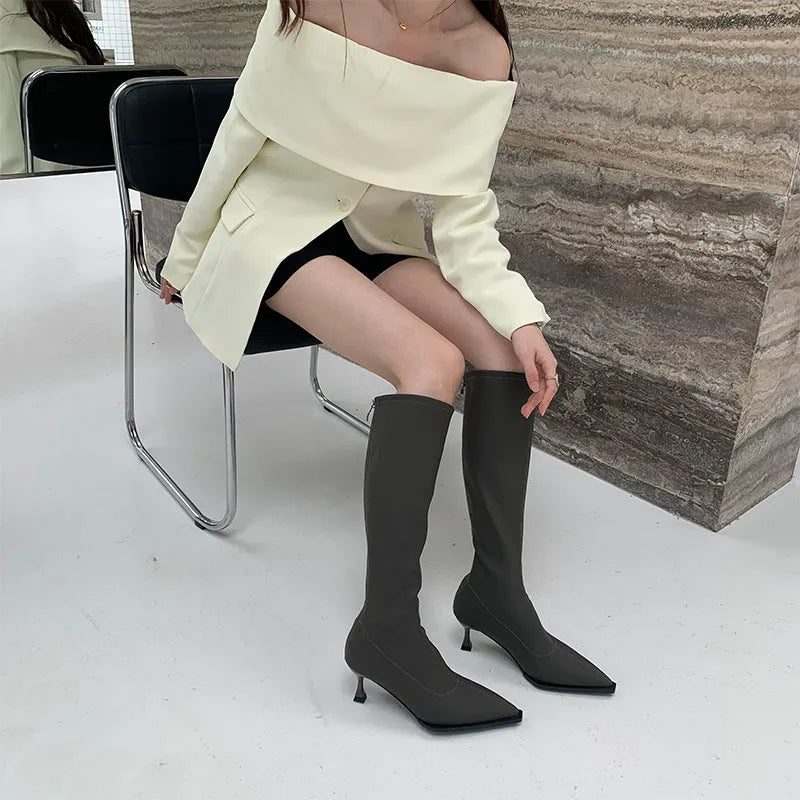Black pointed toe below the knee women's boots with a stiletto heel and back zipper closure on a white background.