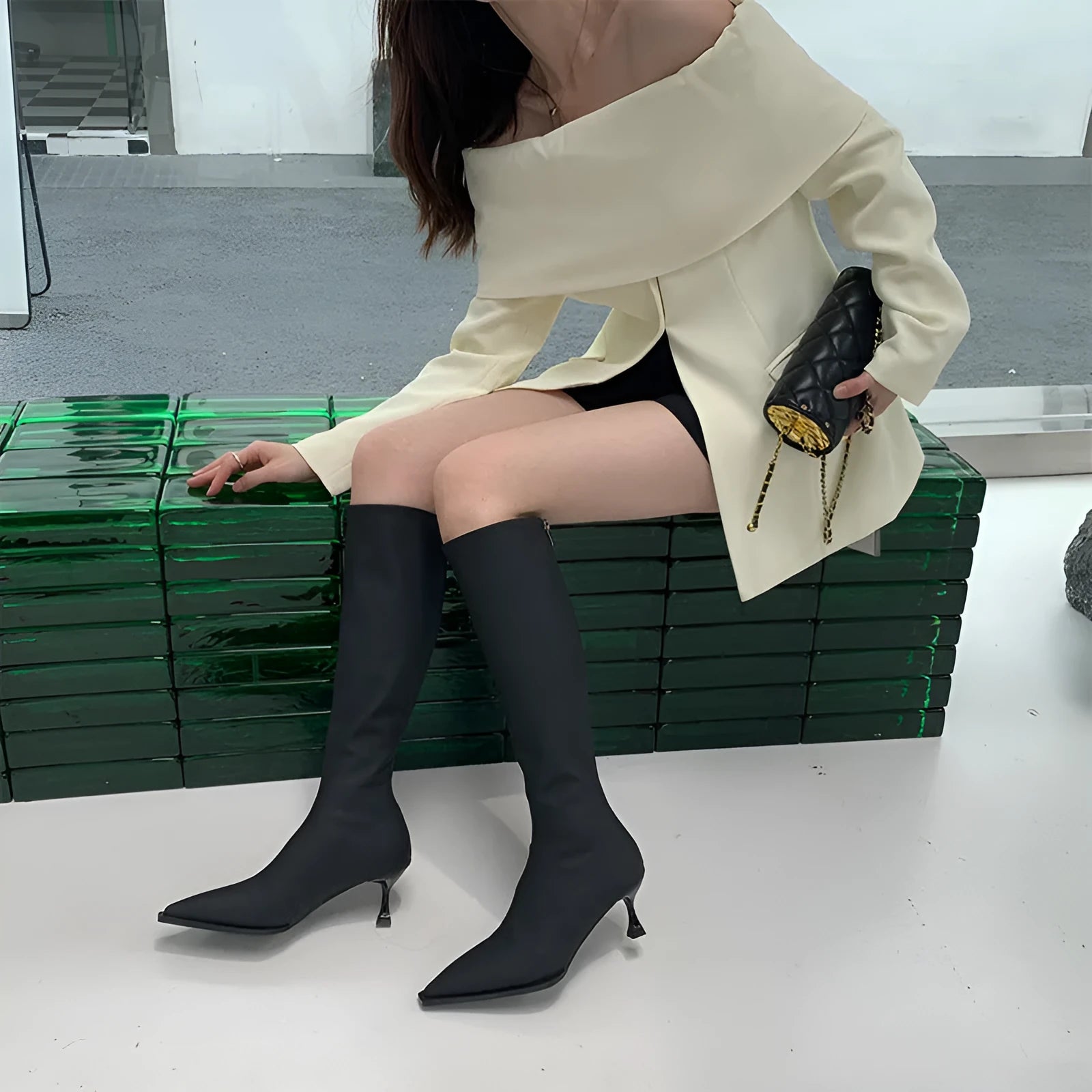Black pointed toe below the knee women's boots with a stiletto heel and back zipper closure on a white background.