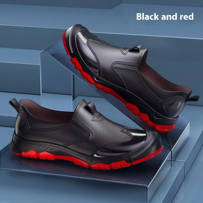 Short black PVC wading boots with a round toe and flat heel on a white background.