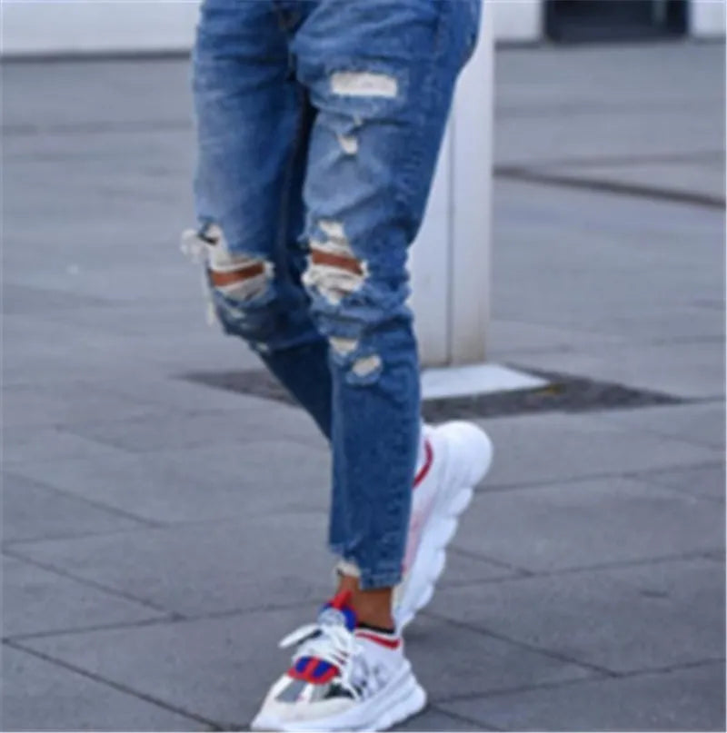 Men's deep blue jeans with hole detail showing cotton fabric texture and contemporary styling