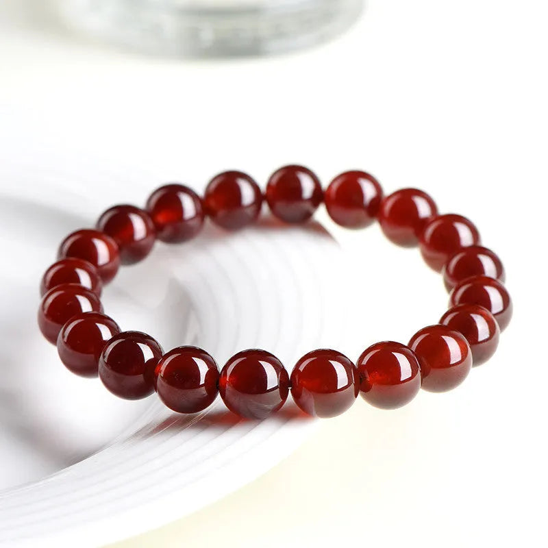 Natural orange red garnet crystal ball bracelet with a traditional metal Ruyi-style clasp.