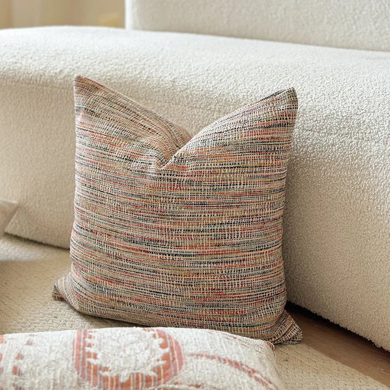 Amber jacquard paisley pillow cover on a sofa, showing textured fabric and botanical pattern.