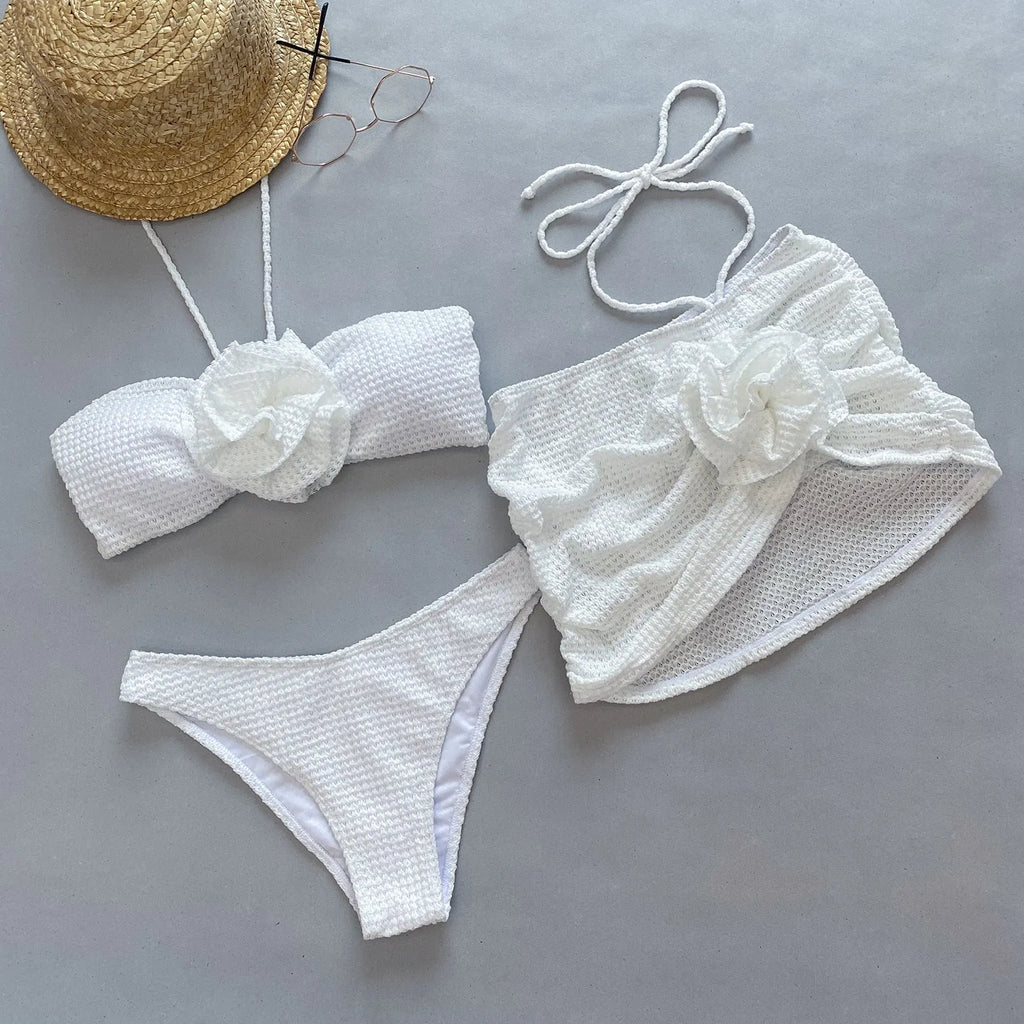 Women's white three-piece bikini set with 3D flower split design on a solid background.