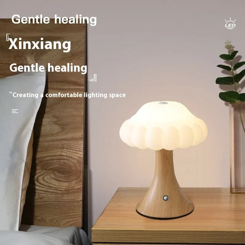 Mushroom-shaped touch control night light in cream colour on a wooden table.