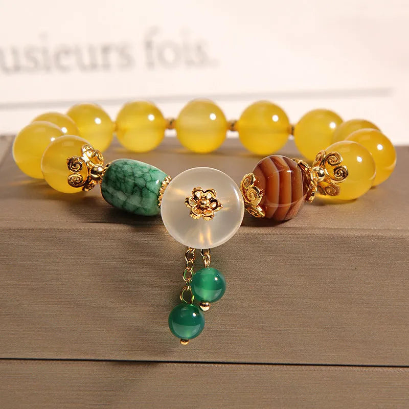 Khaki coloured crystal beads on a gold silk string bracelet, showing adjustable closure.