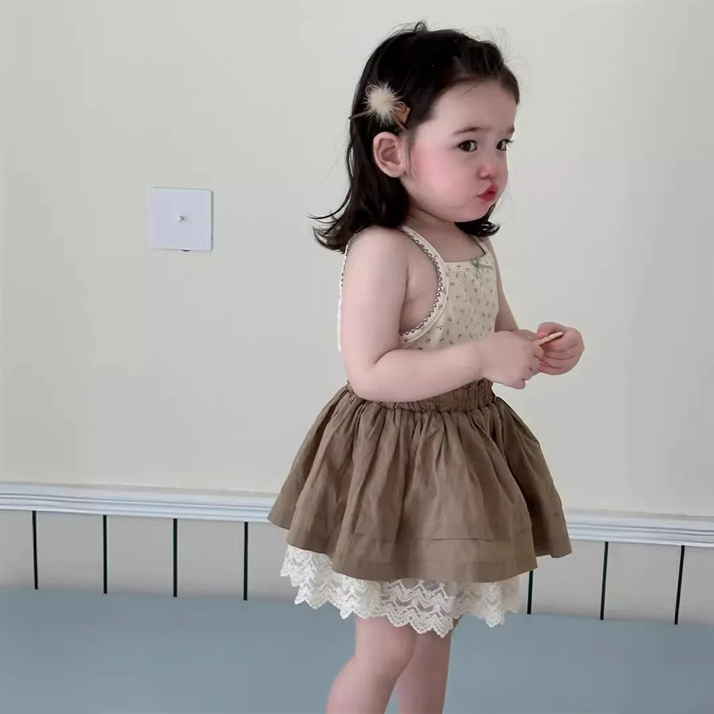 Baby girl wearing floral camisole vest and brown cotton skirt with dots pattern on a white background