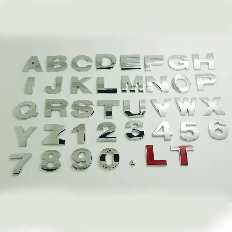 Close-up of a silver metal 3D letter 'A' car sticker with adhesive backing, shown next to a black version.
