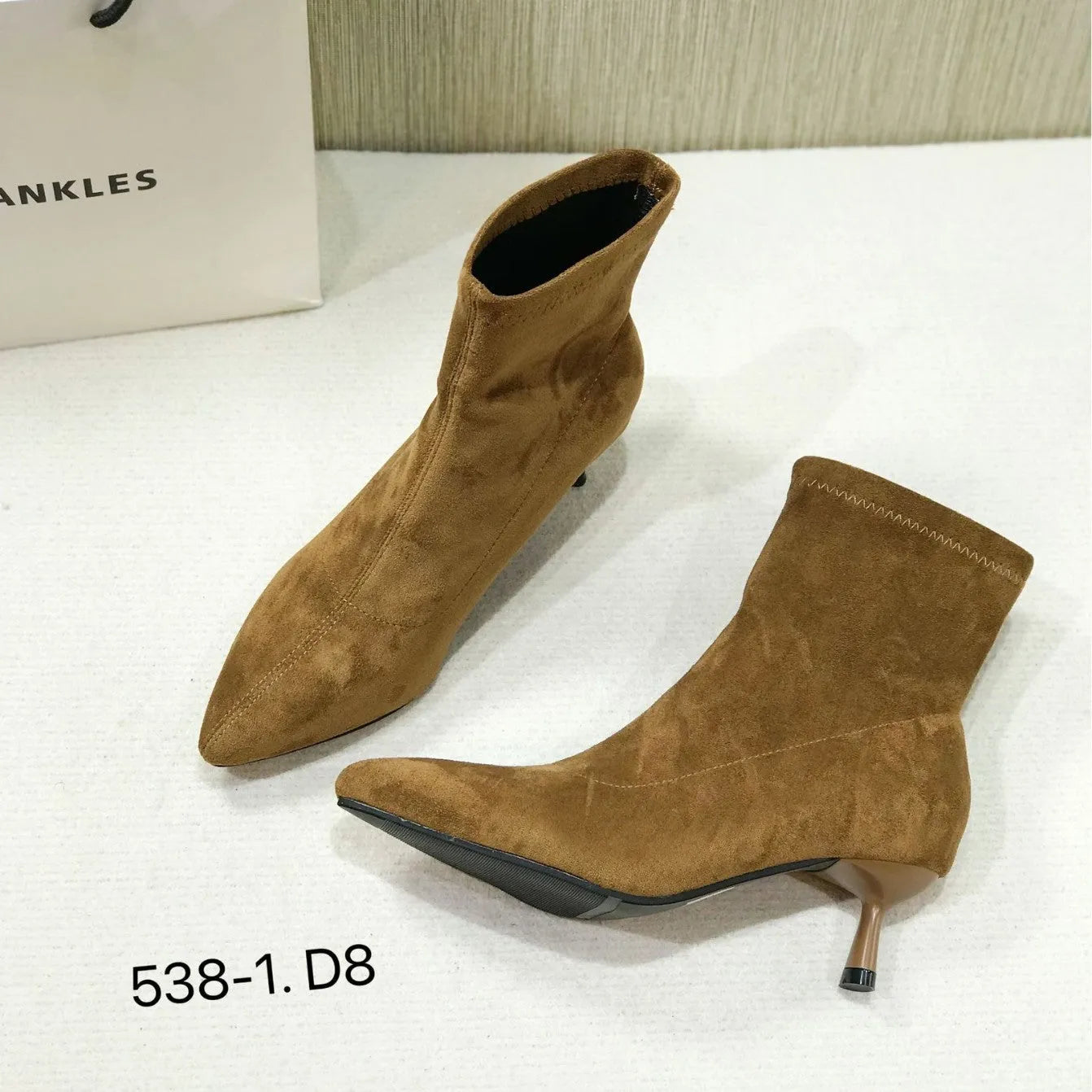 Black pointed toe women's ankle boots with a stiletto heel on a plain background.