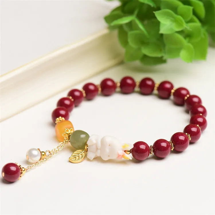 Women's natural cinnabar bracelet with a detailed rabbit pendant, shown in red.