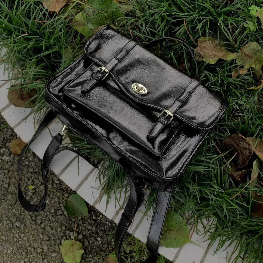 Black college style messenger bag with oil wax leather finish showing shoulder strap and 35cm length