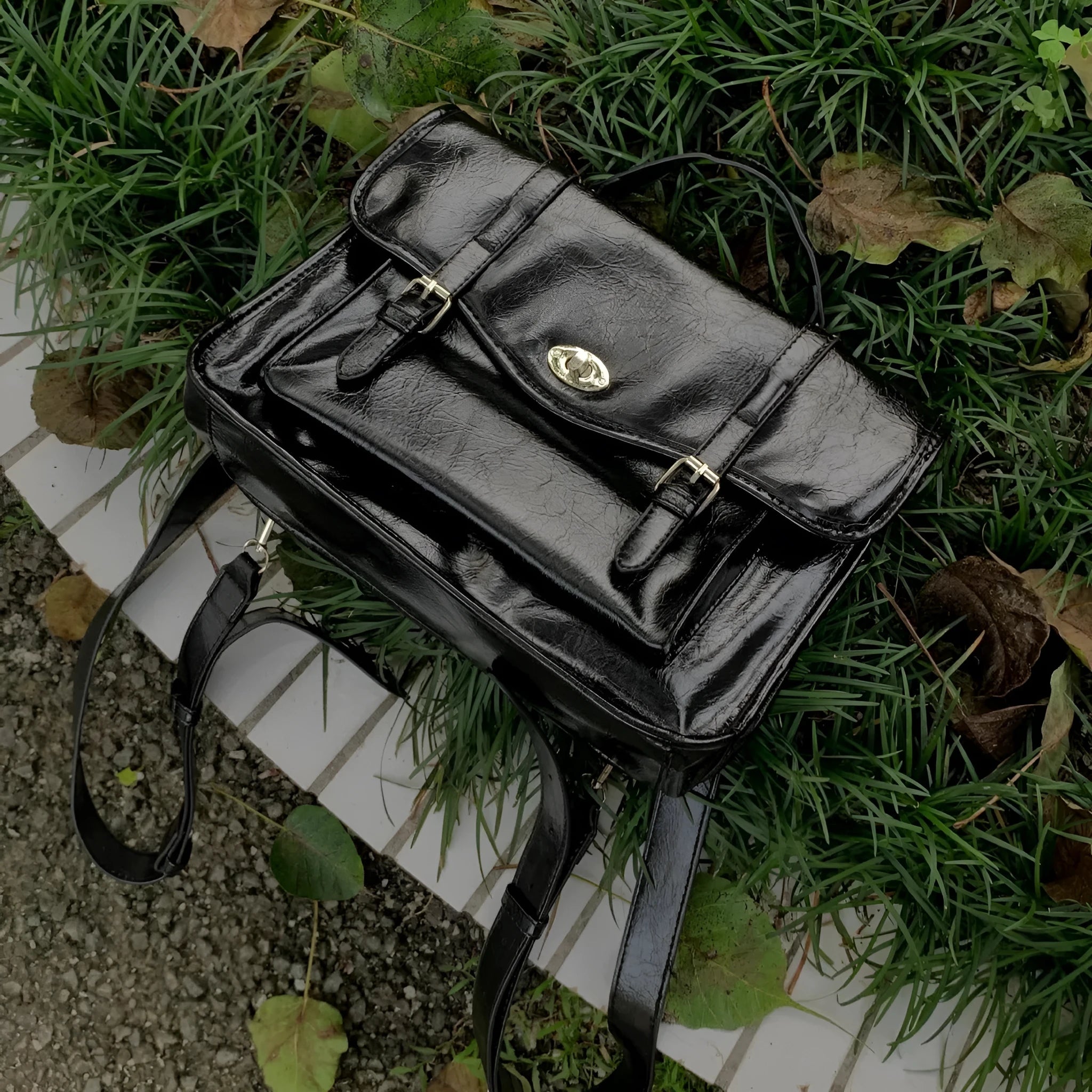 Black college style messenger bag with oil wax leather finish showing shoulder strap and 35cm length