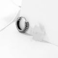 A pair of silver geometric twist earrings on a round base made from stainless steel.