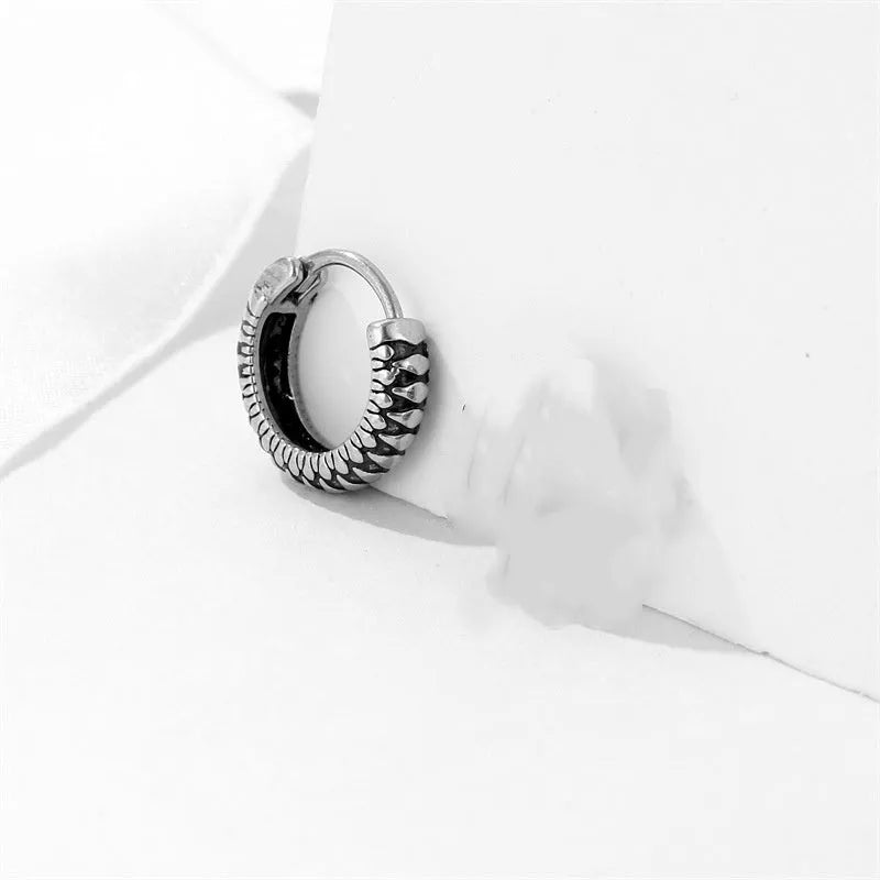 A pair of silver geometric twist earrings on a round base made from stainless steel.