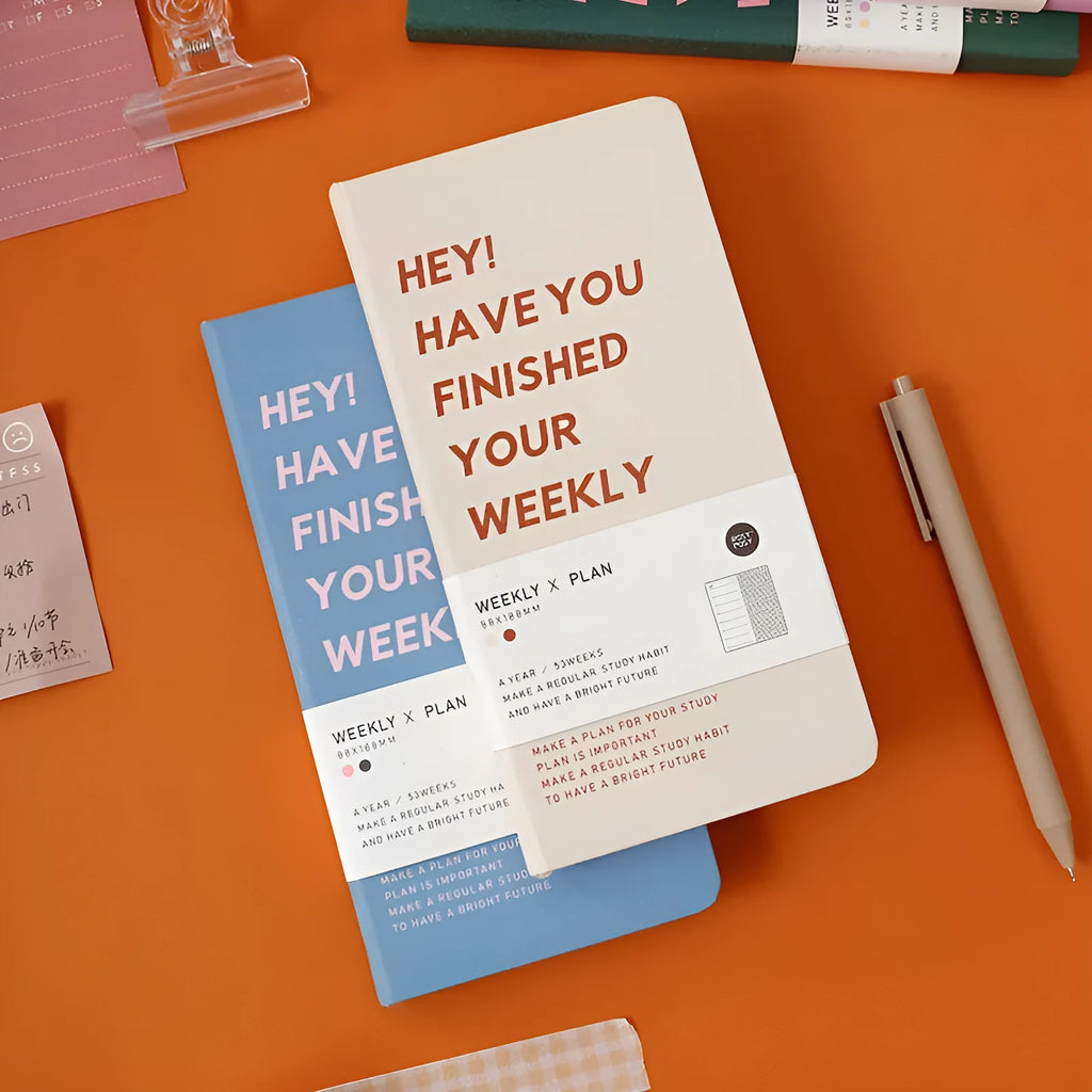 Weekly Plan Diary Handbook with 100 pages in four colour options blue brown green purple on a wooden table