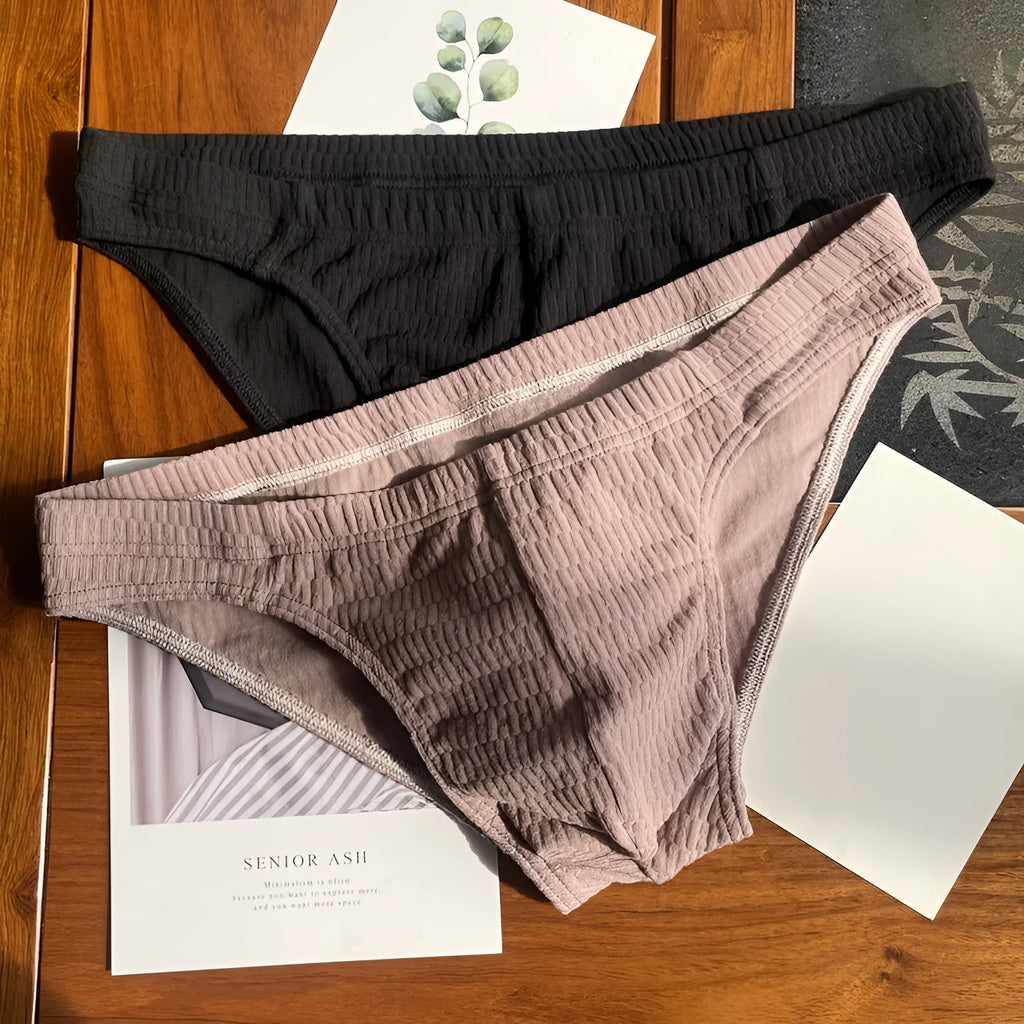 Men's solid colour cotton triangle underwear briefs laid flat, showing mid-waist design in apricot, black, skin colour and white options.