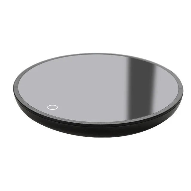 Black coffee mug warmer with temperature switch on desk next to ceramic cup
