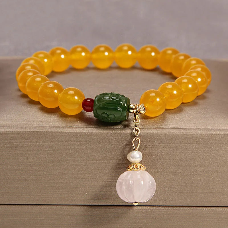 Khaki coloured crystal beads on a gold silk string bracelet, showing adjustable closure.