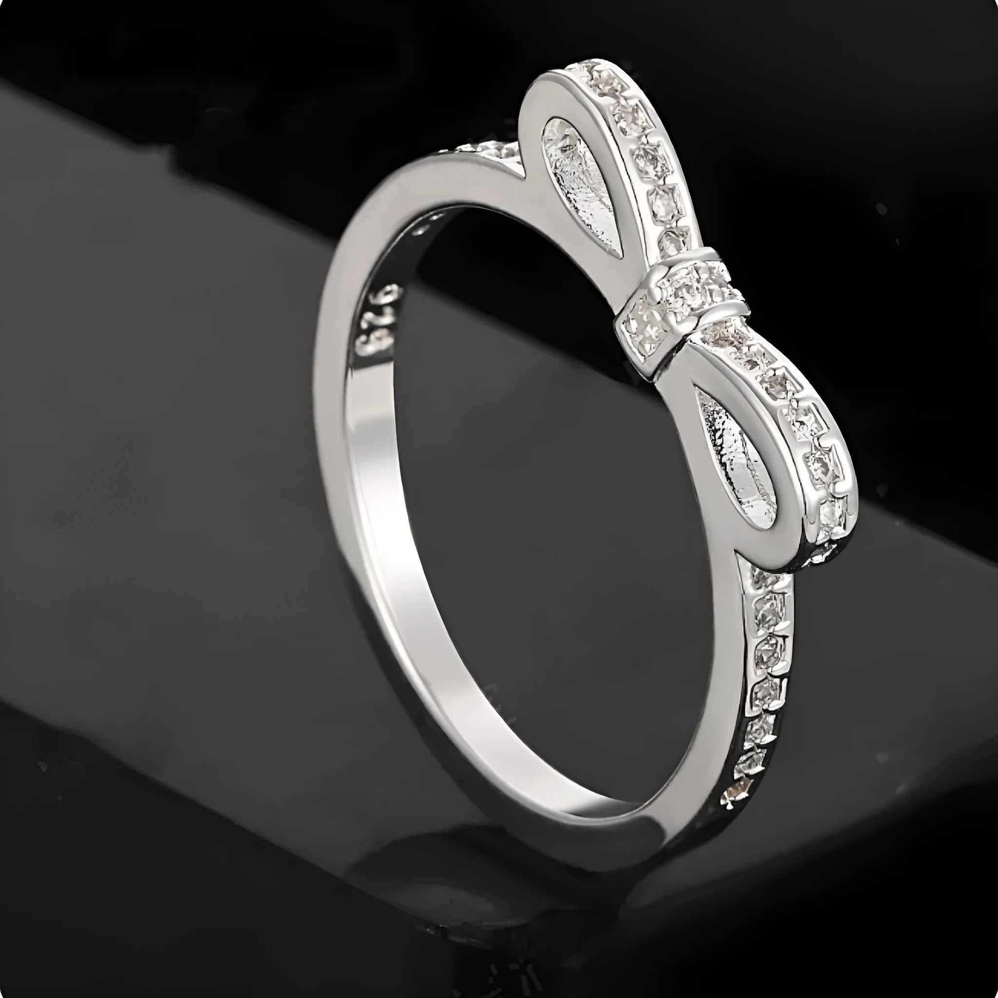 Silver electroplated ring with a bow shape design set with rhinestones and zircon crystals.