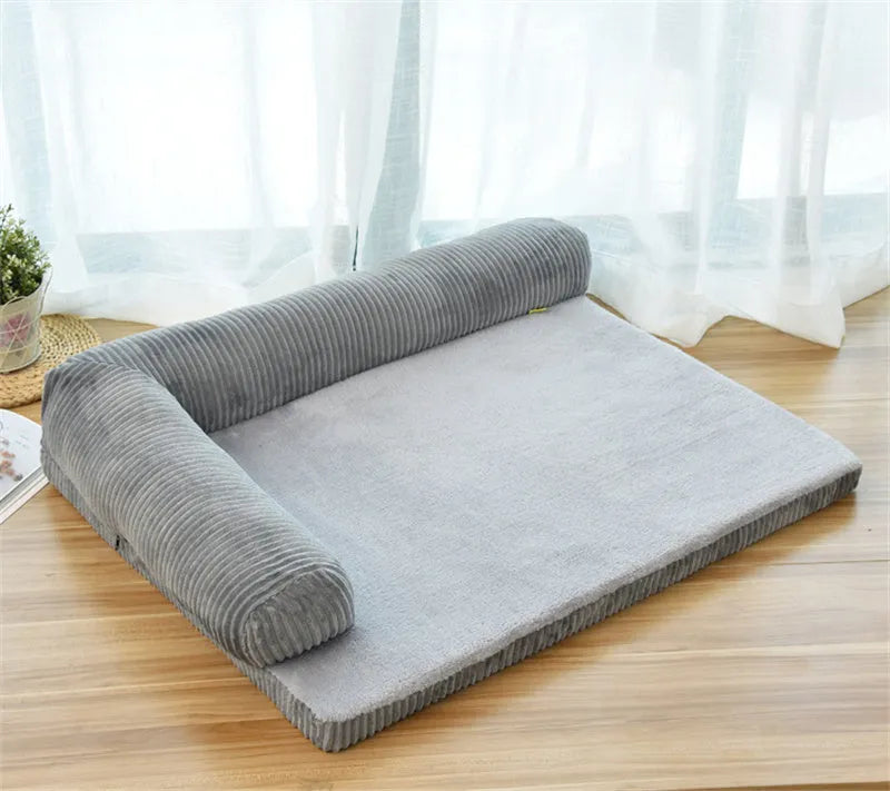 Grey corduroy dog sofa bed with raised sides and a non-slip base on a wooden floor.
