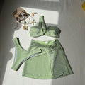Women's one-shoulder glossy polyester swimsuit set in light green, including top, pants, and skirt.