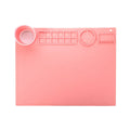 Light blue silicone painting mat with two recessed bowls for holding paint, placed on a wooden table.