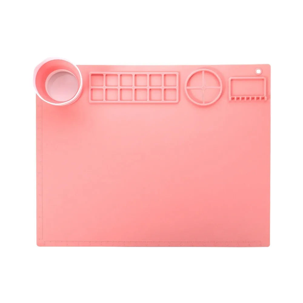 Light blue silicone painting mat with two recessed bowls for holding paint, placed on a wooden table.