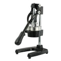 Black or white cast iron manual citrus juicer with stainless steel funnel on a kitchen counter.