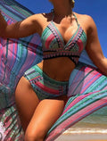Women's blue three-piece bikini set with cross bandage bra, high-waist bottoms, and sheer veils laid flat.