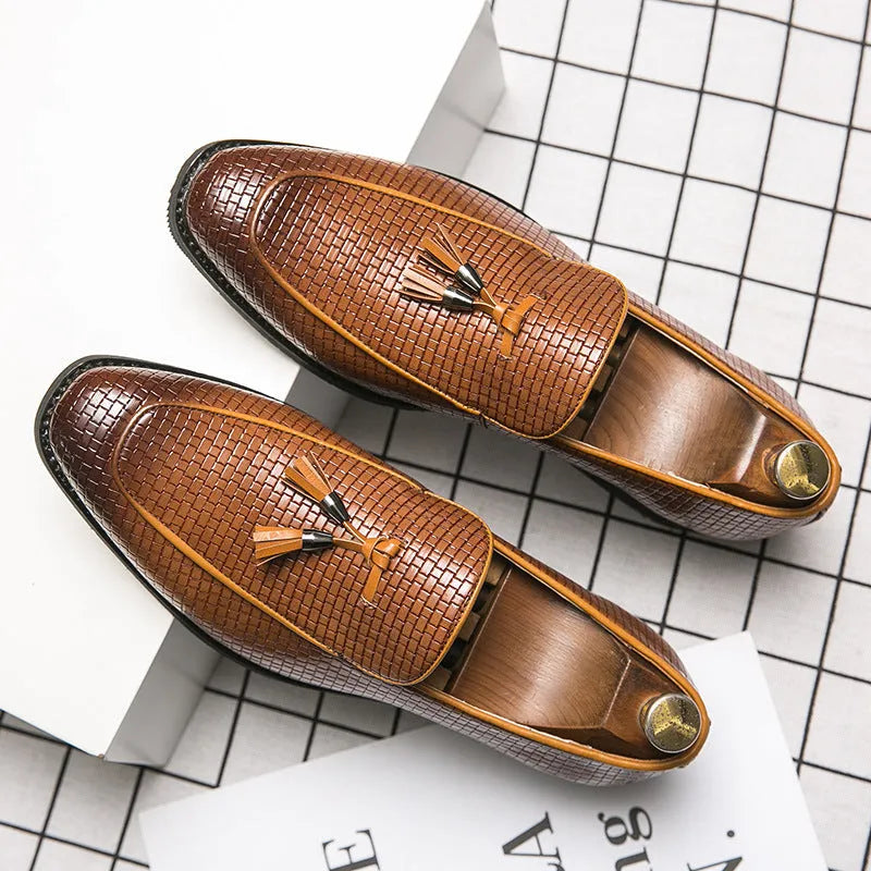 Men's black pointed toe slip-on shoes with a tassel detail on the front.
