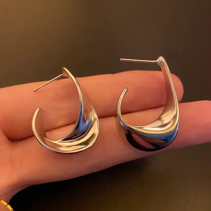 Metal twisted geometric hoop earrings with electroplated gold or silver finish showing round wire design