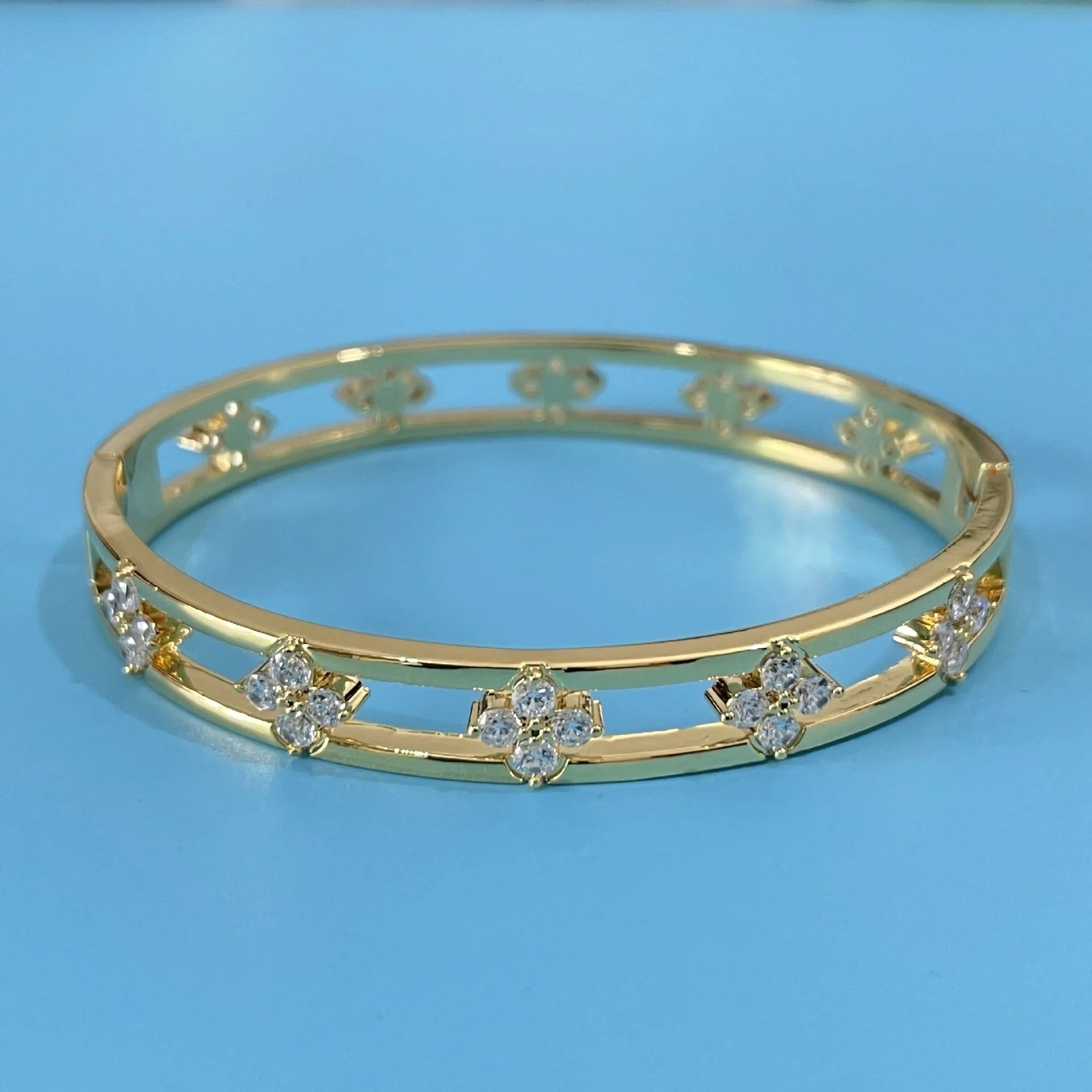 Gold and silver hollow women's bracelets with inlaid zircon stones and four-leaf clover designs.