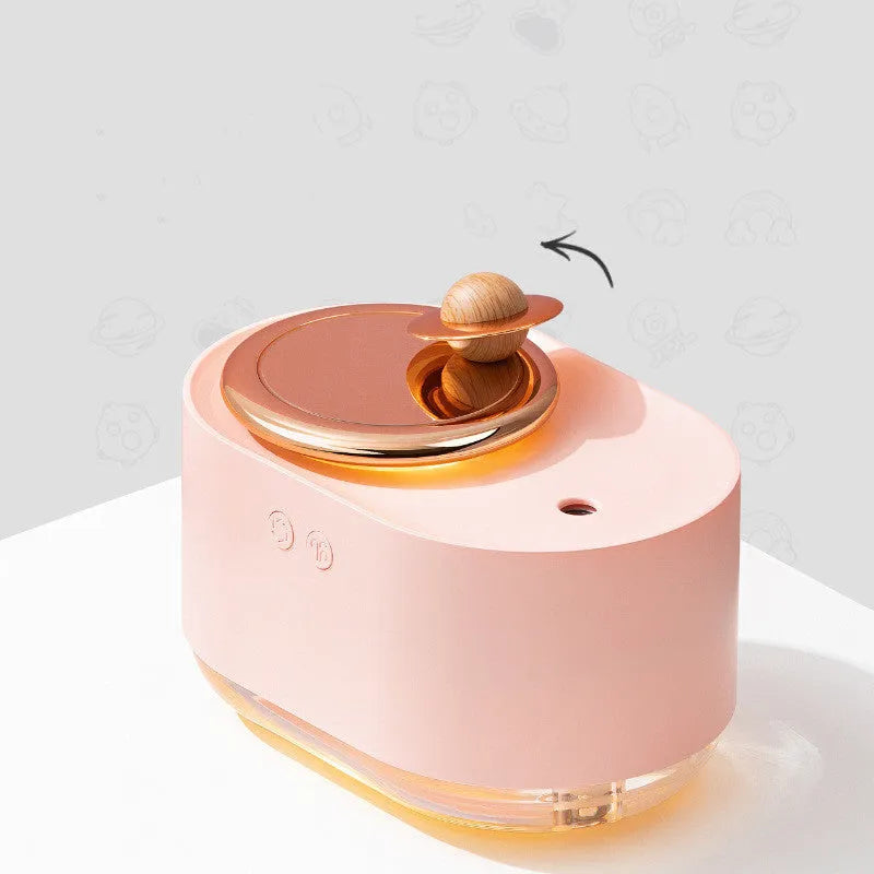 Green rotating planet-shaped humidifier with night light on a wooden table next to a USB cable.