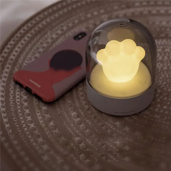 Grey and pink cat paw shaped USB rechargeable night light with music box on a desk