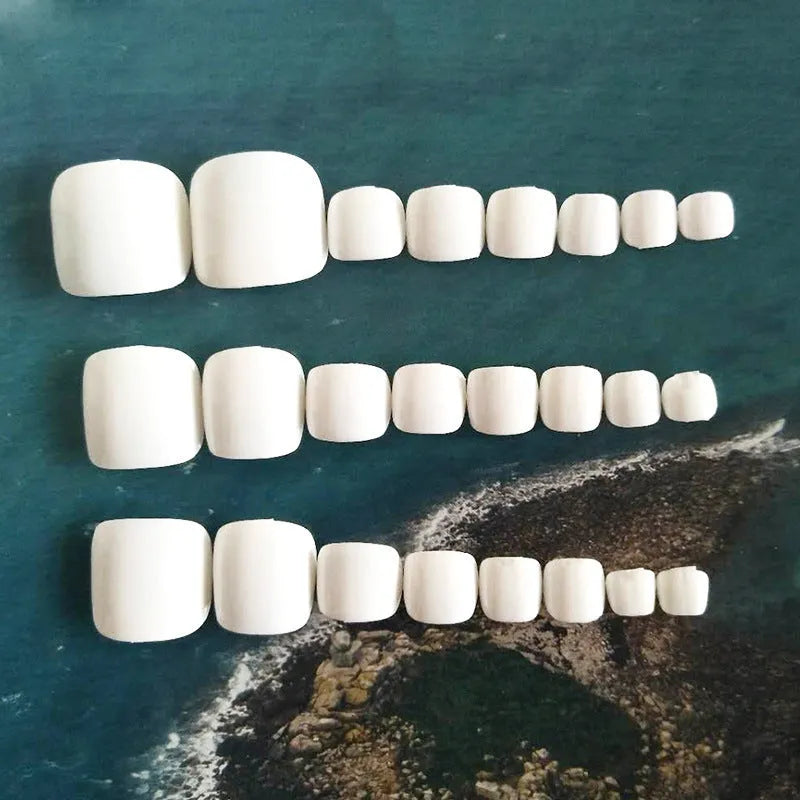 Set of white false nails with a starry sky pattern design, laid out for press-on application.