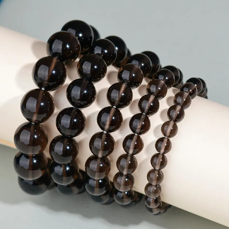 Hand-woven round obsidian bracelet with crystal beads in various colour options on a wrist.